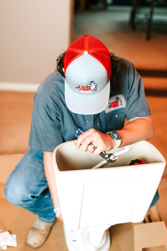 Colby, Bear’s Plumbing technician, installing a toilet while protecting the customer’s floor in Spring, TX