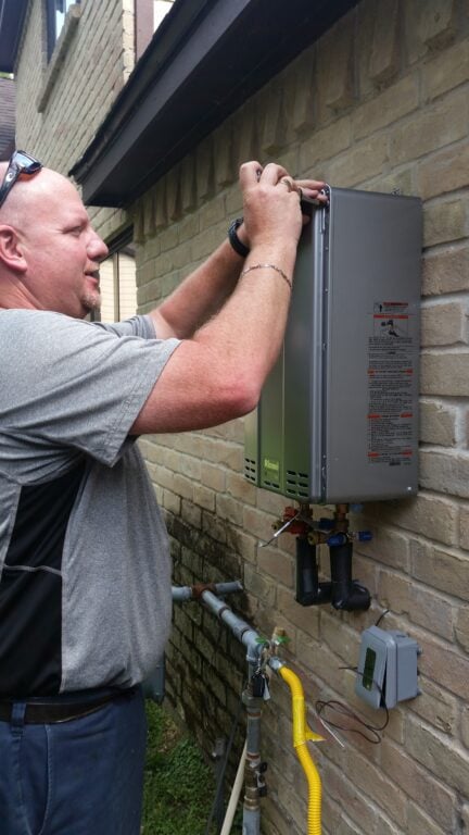 Bear installing a tankless water heater on the exterior wall of a home in Spring, TX