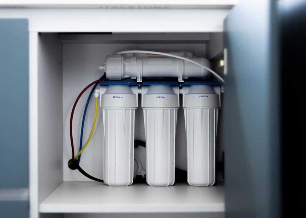 Three-stage water filtration system installed inside a kitchen cabinet in Tomball, TX